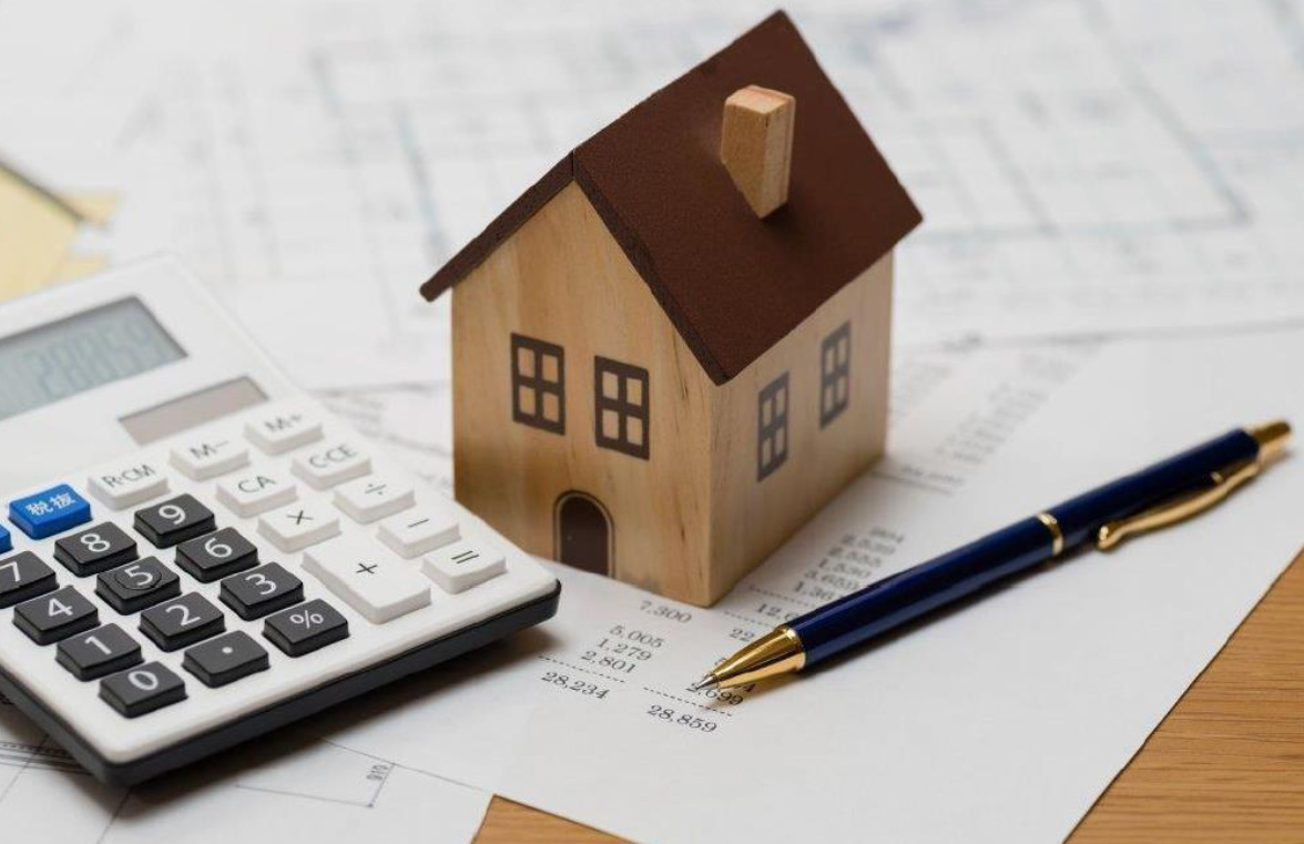 A calculator with a house sitting on paperwork with the final closing costs for a home purchase